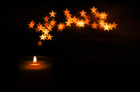 Aromatic candle with flame and star shape bokeh on dark background for Thanks giving and Christmas day.の写真素材