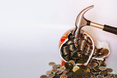 Hammer breaking piggy bank with Thai baht coins on white backgroundの写真素材