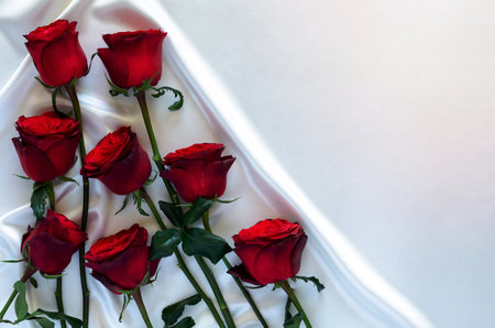 Red roses put on white satin cloth background for anniversary, mother and Valentine day concept.の写真素材