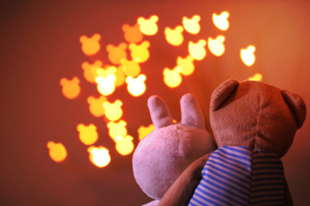 Teddy bear and rabbit dolls acting as lover sitting together to watch bear shape bokeh light background that have space for text.の写真素材