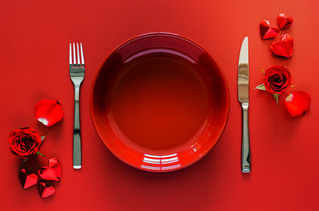 Valentines dining concept with red plate, fork and knife put on red table with rose and love shape paper fold.の写真素材