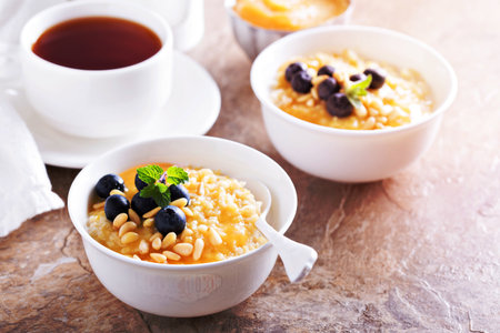 Cooked millet porridge with lemon curd,  blueberry and pine nutsの写真素材