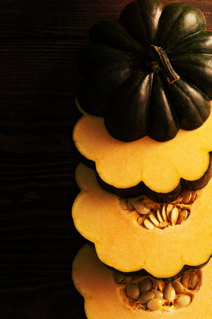 Sliced raw acorn squash on dark background overhead shotの写真素材