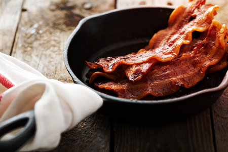 Sizzling hot bacon pieces in a cast iron skilletの写真素材