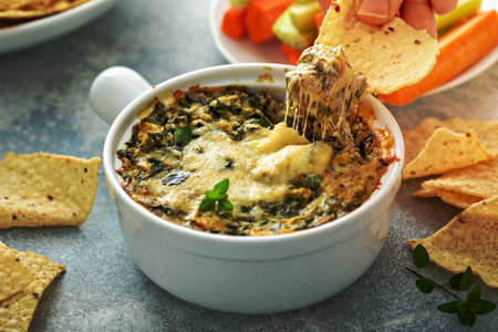 Artichoke spinach dip in a baking dish with a cheese pullの写真素材