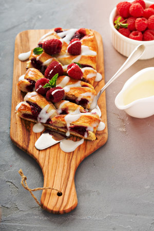 Braided raspberry danish with glaze and fresh berriesの写真素材