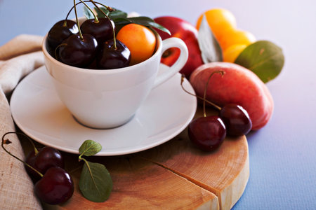 Fresh stone fruits cherries peaches plums in white cupの写真素材