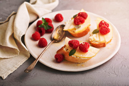 Open faced sandwiches with cheese, fresh pears and raspberryの写真素材