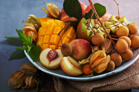 Tropical fruit plate with mango, apricots, longan and kiwiの写真素材
