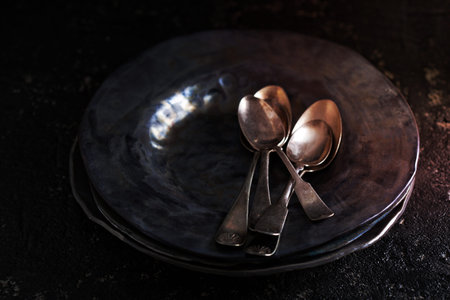 Black handmade ceramic plates with old vintage spoonsの写真素材