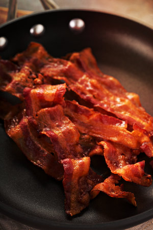 Cooked sizzling hot tasty crispy bacon on a skillet ready for breakfastの写真素材