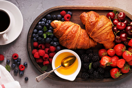 Croissants with fresh berry and honey and a cup of coffee for breakfastの写真素材