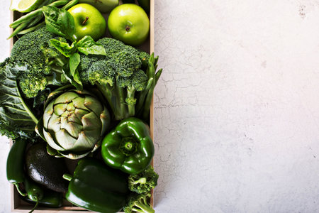 Variety of green vegetables and fruits in a crate on the tableの写真素材