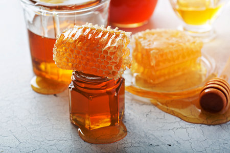 Various types of honey in glass jars and honeycombの写真素材