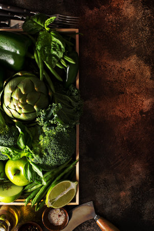 Variety of green vegetables and fruits in a crate on the tableの写真素材