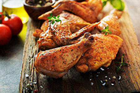 Pieces of grilled or smoked chicken on a wooden boardの写真素材