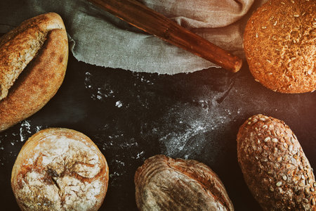 baked various loaves of bread on a black background, empty space in the middle, top view, vintage toningの写真素材