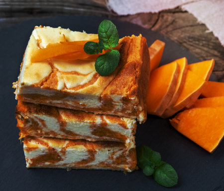 square pieces of baked cheesecake cottage cheese with pumpkin and fresh pieces of vegetable, top viewの写真素材