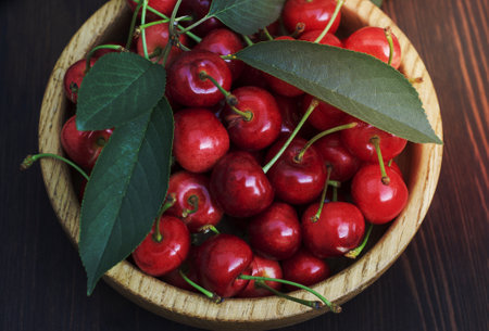 Ripe red cherry in a wooden plate on the table, close-upの写真素材