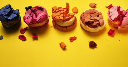 broken round macarons with crumbs on a yellow background, delicious dessert, top viewの写真素材