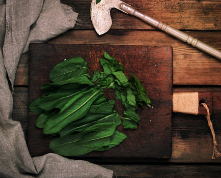 chopped green sorrel leaves on an old brown wooden board and an old iron metal knife, top viewの写真素材