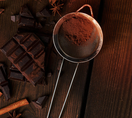 broken pieces of dark chocolate, cinnamon sticks and star anise on a brown wooden table, top viewの写真素材