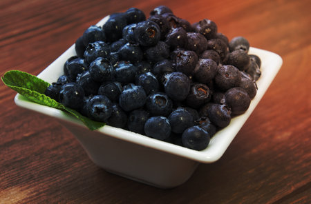 fresh bilberries or blueberries in small bowls on a rustic table, selective focusの写真素材
