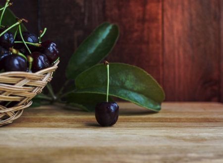 One cherry in the middle of the table, next to a wicker basket with a cherryの写真素材