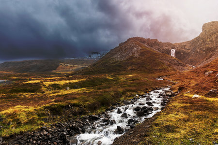 Unknown waterfalls and fresh water stream in Iceland wilderness under stormy weather .の写真素材