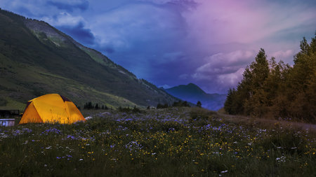Tent at camp site in the middle of rocky mountains with cloudy skyの写真素材