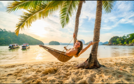 Female tourist swinging in hummock on tropical beach, Koh Mak Thailandの素材