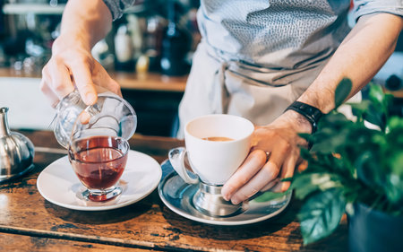 A young male getting ready to prepare a tea in a modern barの素材