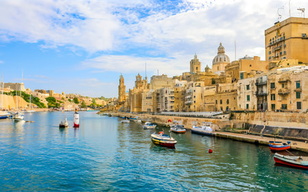 view of Valletta embankment street with lots of boats on water in harbour, Maltaの素材