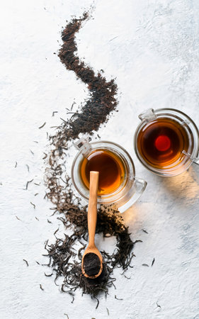 Black tea with tea in wooden bowl and glass cup over white texture backgroundの素材