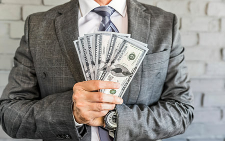 closeup businessman in suit holding one hundred 100 dollar bill. money conceptの素材