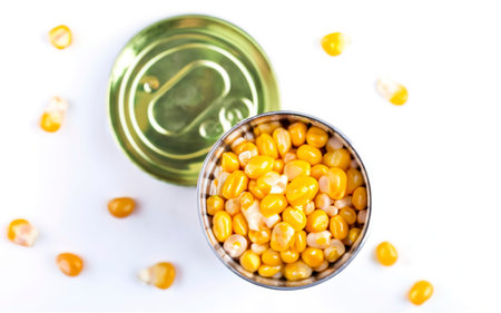 Grains of sweet canned corn in a can. Isolated on white backgroundの素材