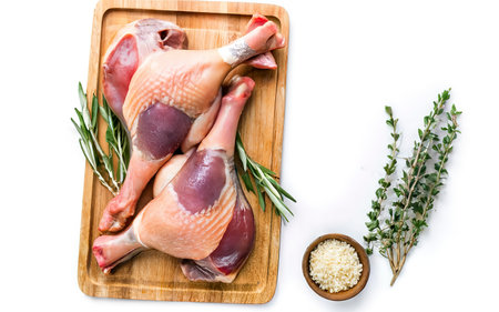 Raw Duck legs on a wooden tray. Isolated on white backgroundの素材