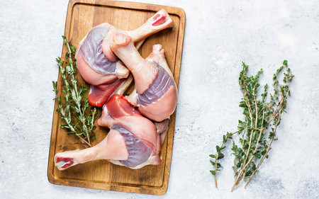 Raw Duck legs on a wooden tray. Isolated on white backgroundの素材