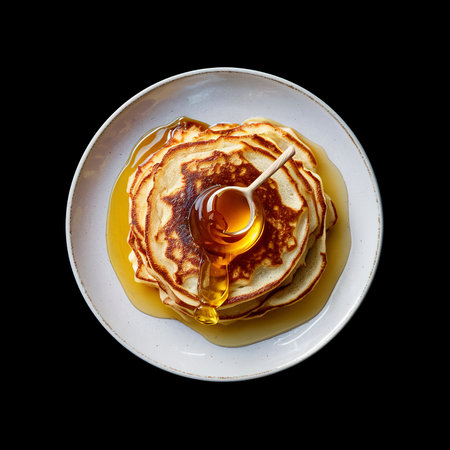 cooked sweet pancakes with honey in a plate isolated on black backgroundの素材