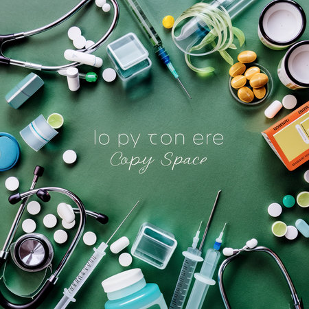 Stethoscope, medical pills and syringes on green background with copy spaceの素材