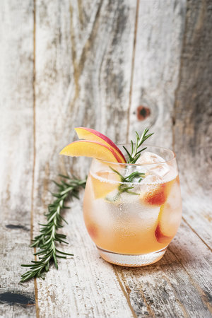 Peach and rosemary fizz cocktail on a wooden background.の素材