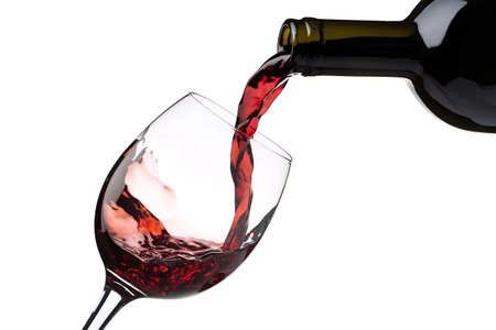 A photo of a clear wine glass being filled with red wine from a dark-colored bottleの写真素材