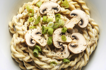 A photo of a plate of creamy pasta garnished with sliced mushroomsの写真素材
