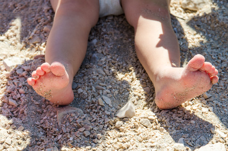 Little kid sitting on the sand and playing with plastic toys. Travel photo of girl on the beach. Summer vacation in Croatia.の写真素材