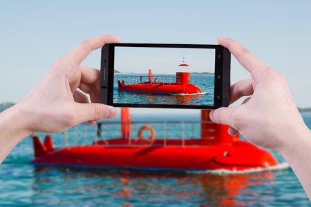 Hand man holding and taking picture with mobile. Tourist photograph semi submarin in vacation at Pakostane in Croatia during holiday. Place for advertising logo smartphone travel concept.の写真素材