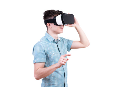 Man in blue shirt with glasses of virtual reality on white isolated background. Young guy in VR headset is looking at interactive screen. Playing mobile game app on device.の写真素材