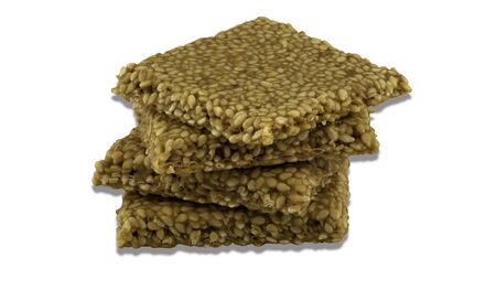 Til chikki on white background is an Indian sweet dish made with jaggery and sesame seeds.の写真素材