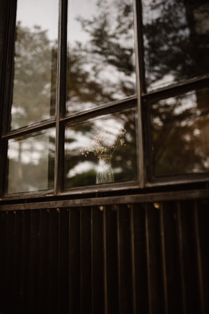 A shot of a gloomy window on a cafe, with flowers as decoration.