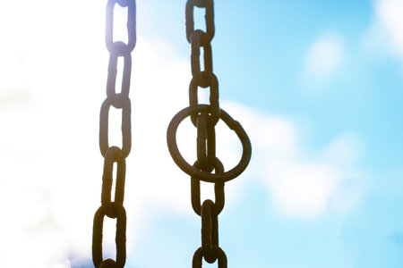 Vertical hanging rusty chain. Sunlight, blue background. For text area