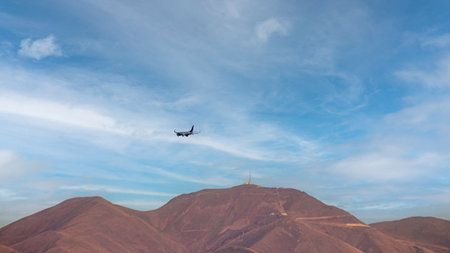 A passenger airplane flying in a cloudy, bright sky with Palandoken Mountain. Travel, tourism sceneの写真素材